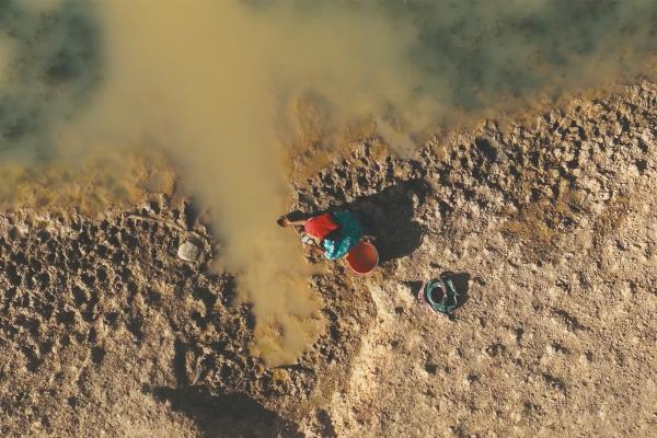 Overhead shot of a person in a sandy desert retrieving water