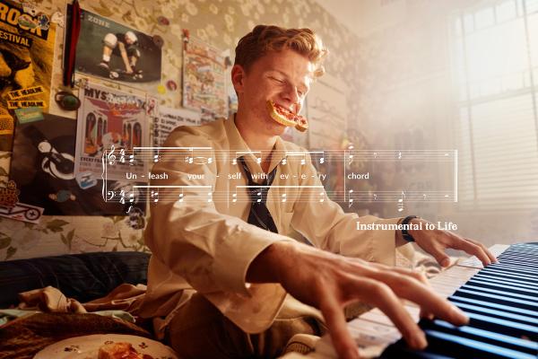 Instrumental to Life — Kawai Young man oplaying piano with a piece of toast hanging out of his mouth. There is a white graphic of sheet music superimposed over the image