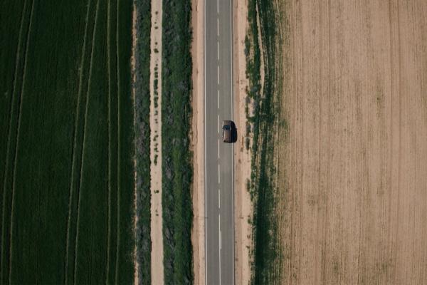 Viva Vivir — The Directorate-General for Traffic (DGT) Bird's eye view of a single car on a road, with brown dirt on one side of the road and green grass/trees on the other