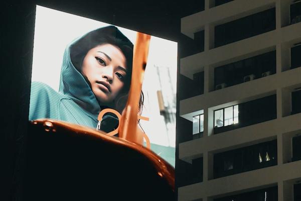 Decaf Billboards — Nestlé A billboard outside at night. On the billboard, coffee flows down into a mug. Behind the liquid, a woman wearing a jacket with a hood.