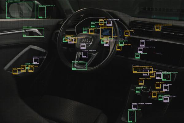 Audi Reader — Audi A dark, interior shot of a car's dashboard and steering wheel, overlaid with numerous green and yellow bounding boxes and text labels. The labels identify various car features and controls, such as "VIRTUAL MIRROR," "MIRRORS CONTROLS," "DOOR LOCK," "CHILD LOCK," "CRUISE CONTROL," "DRIVE ASSIST," "CENTRAL INDICATOR," "CLIMATE DISTRIBUTION," and "PARKING BRAKE." The steering wheel has an Audi logo.