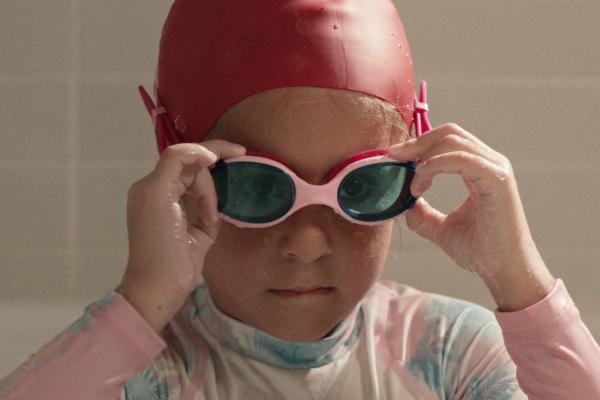 Athletes in the Making — AAMI Young child in swim cap putting on swimming goggles