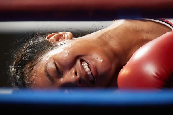 The Boxer — Colgate woman boxer laying face down on the canvas with a smile on her face