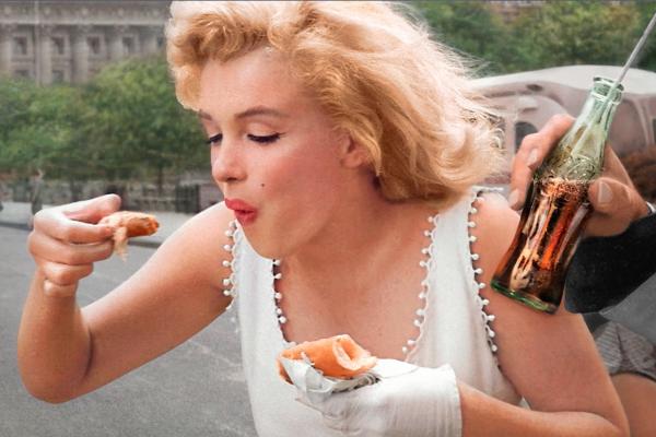 Foodmarks — Coca-Cola Marilyn Monroe eating while a hand holds a Coca-Cola bottle frame right
